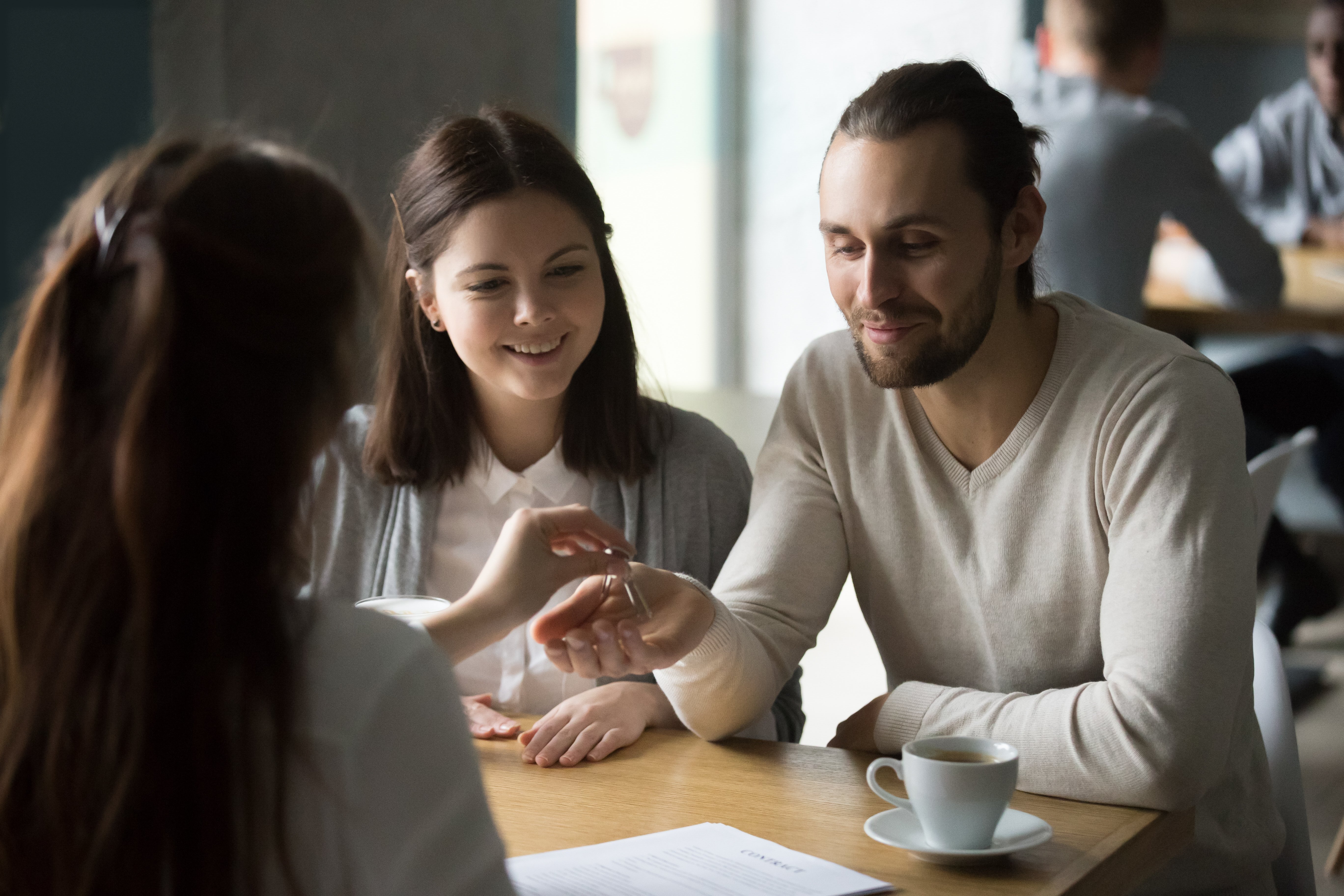 happy-millennial-couple-getting-keys-to-new-house-from-realtor